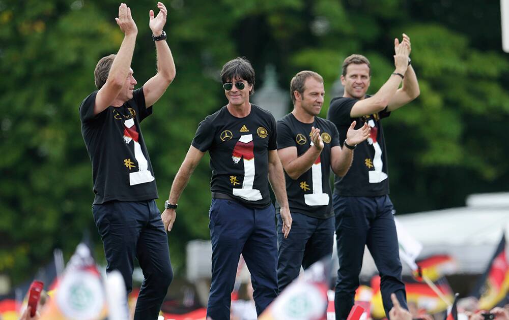 The German coaching team, from left, goalkeeper coach Andreas Koepke, head coach Joachim Loew, assistant coach Hansi Flick and team manager Oliver Bierhoff wave from the stage after the arrival of the German national soccer team in Berlin .