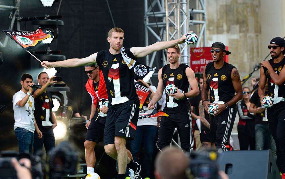 Per Mertesacker and his teammates walk onto the stage after the arrival of the German national soccer team in Berlin.