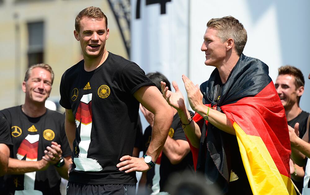 Goalkeeper Manuel Neuer, left, and Bastian Schweinsteiger walk onto the stage during fan party after the arrival of the German national soccer team in Berlin .