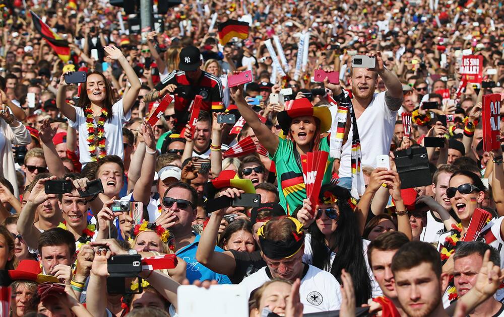 Fans enjoy the atmosphere as they wait for the German national soccer squad during the German team victory ceremony , near the Brandenburg Gate in Berlin