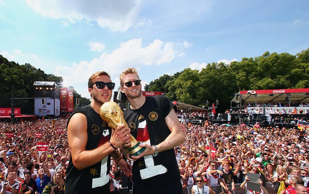 German national soccer players from left: Mario Goetze and Andre Schuerrle celebrate on stage at the German team victory ceremony , near the Brandenburg Gate in Berlin.