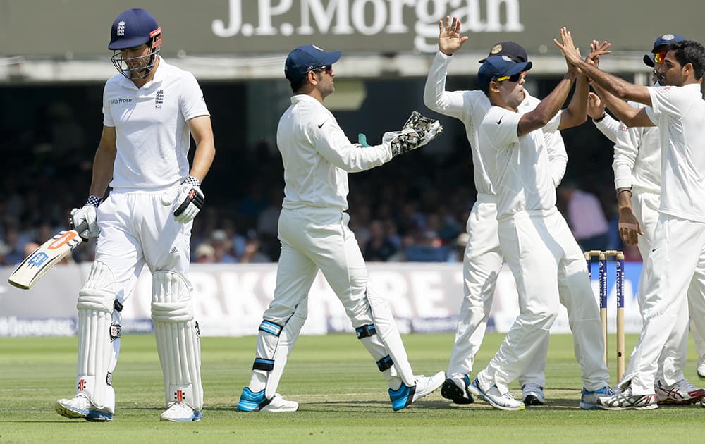 India's players celebrate taking the wicket of England's captain Alastair Cook during the second day of the second test match between England and India at Lord's cricket ground in London.