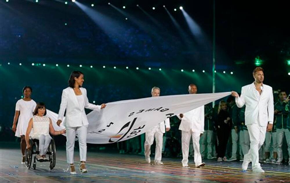 The Commonwealth Games flag is carried into the arena by former athletes including Australian swimmer Ian Thorpe, right, during the opening ceremony for the Commonwealth Games 2014.