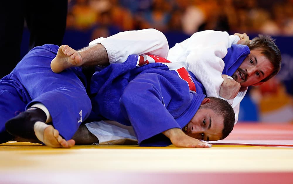 England's Colin Oates , rear, pushes down Andreas Karassas from Cyprus to win the Men -66kg Judo final bout at the Commonwealth Games 2014 in Glasgow, Scotland.