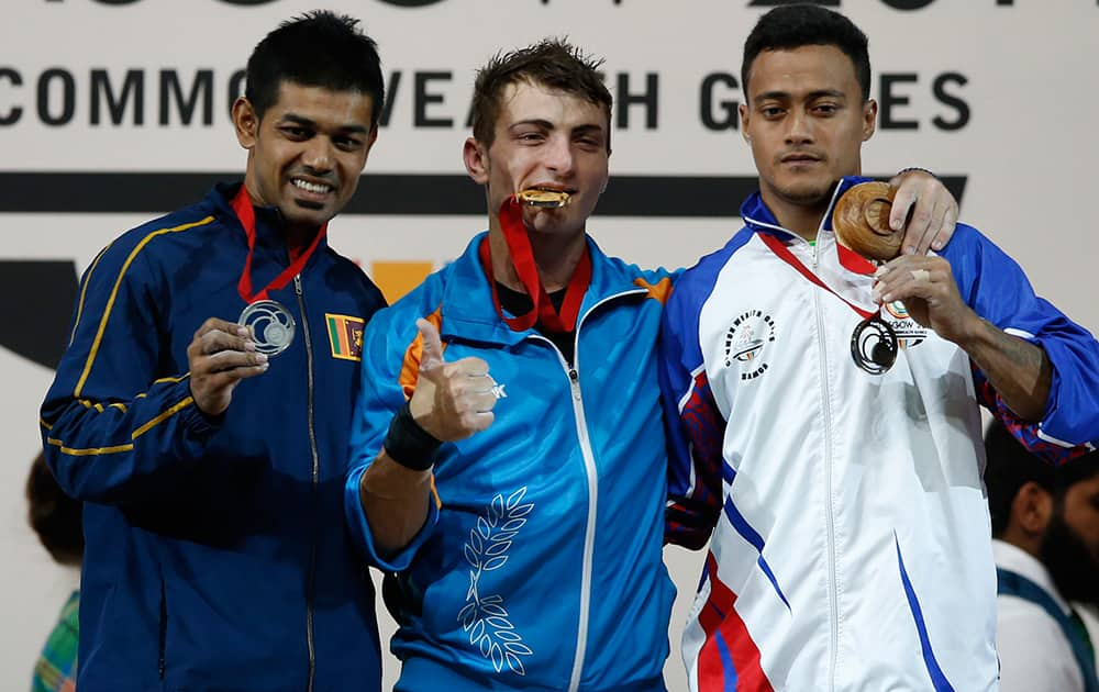 Gold medalist Dimitris Minasidis, of Cyprus, centre, Sudesh Peiris of Sri Lanka, left, silver medal and Vaipava Ioane of Samoa bronze medal pose for photographs after the medal ceremony for the men's 62 weightlifting contestat the Commonwealth Games Glasgow 2014, in Glasgow, Scotland.