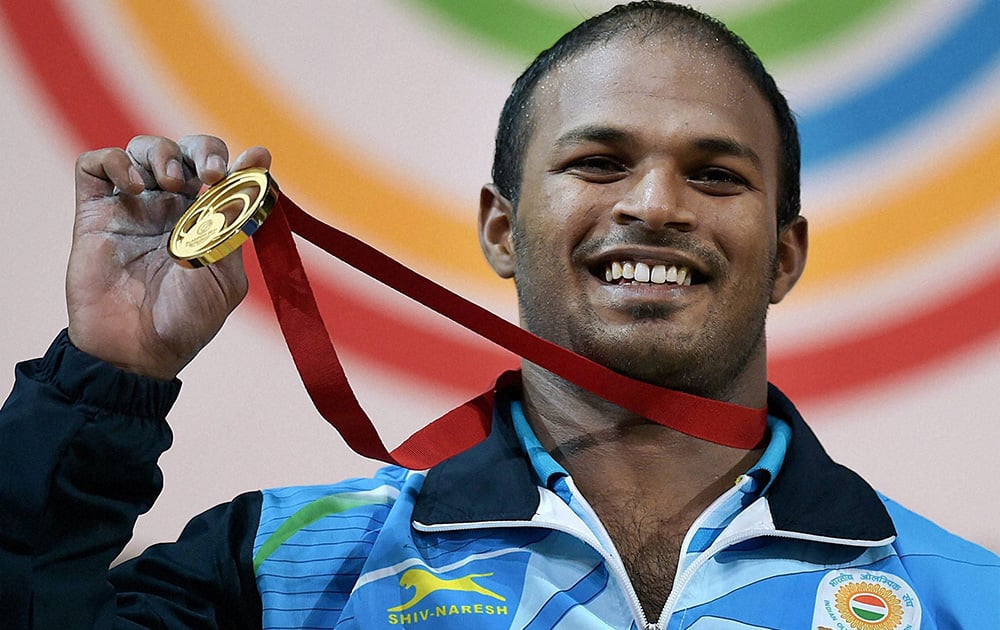 Sathish Sivalingam of India shows the medal after winning the gold in the Men's Weightlifting 77kg category during the Glasgow 2014 Commonwealth Games at Scottish Exhibition And Conference Centre in Glasgow,Scotland.