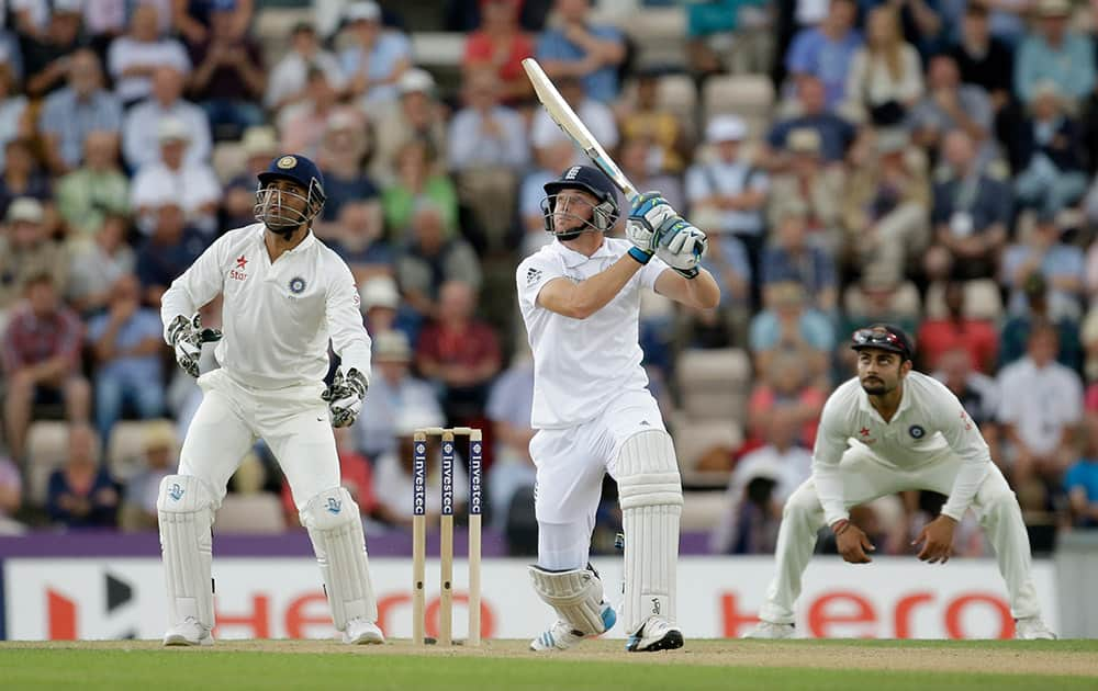 England wicketkeeper Jos Buttler hits a shot as India's captain and wicketkeeper Mahendra Singh Dhoni, left, and Virat Kohli, right, look on during the second day of the third cricket test match of the series between England and India at The Ageas Bowl in Southampton, England