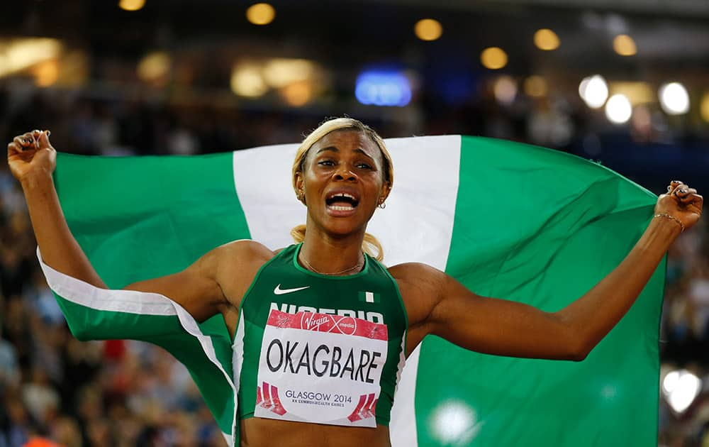 Blessing Okagbare, of Nigeria, holds up the national flag of Nigeria as she celebrates after wining the women's 100 meter final, at Hampden Park stadium in Glasgow during the Commonwealth Games 2014 in Glasgow.