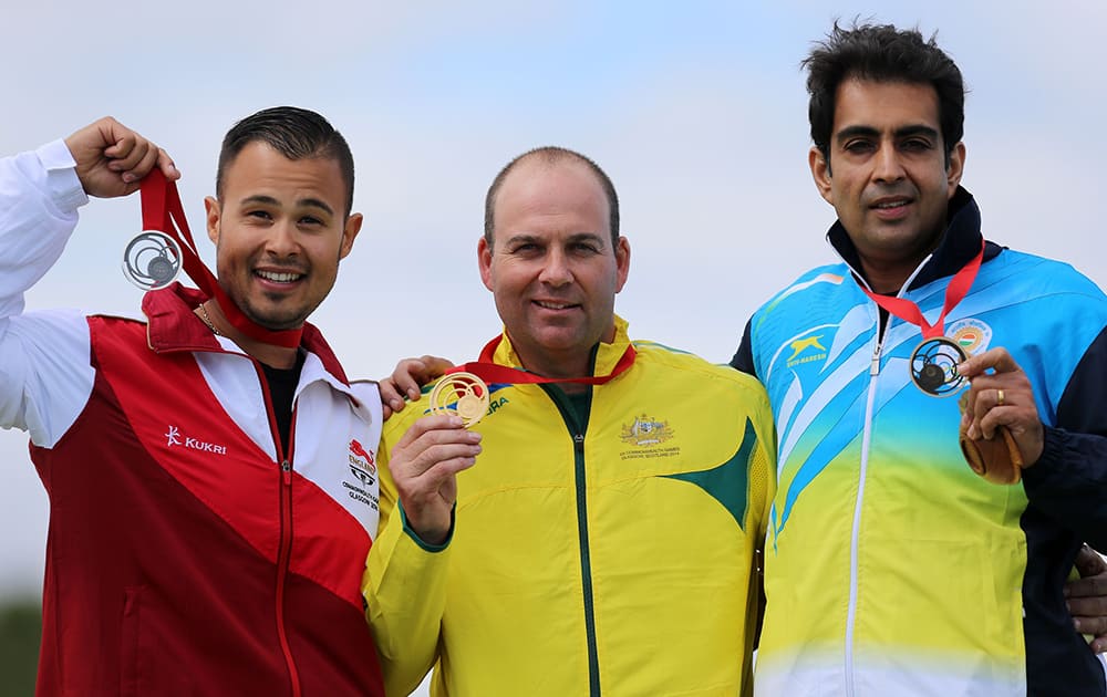 Australia's Adam Vella, center, celebrates winning the gold medal in the Trap Men with silver medalist Aaron Heading, left, and bronze medalist India's Manavjit Singh Sandhu at the Barry Budden Shooting Centre, during the 2014 Commonwealth Games.