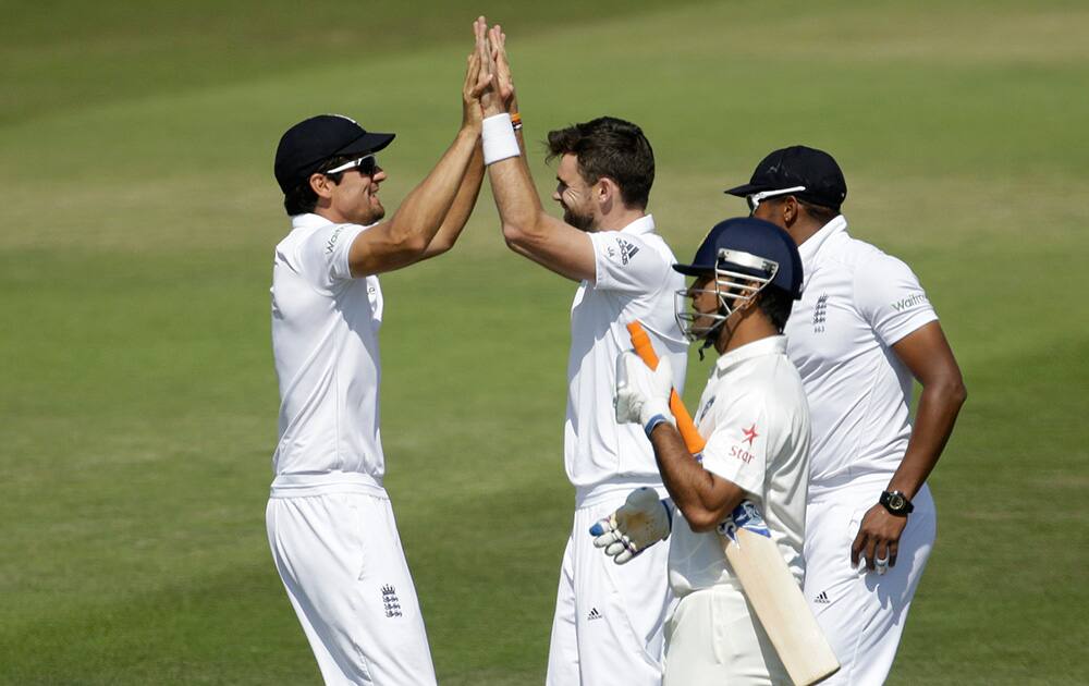 England's James Anderson celebrates with captain Alastair Cook beside Chris Jordan after taking the wicket of India's captain and wicketkeeper Mahendra Singh Dhoni, second right, during the fourth day of the third cricket test match of the series between England and India.