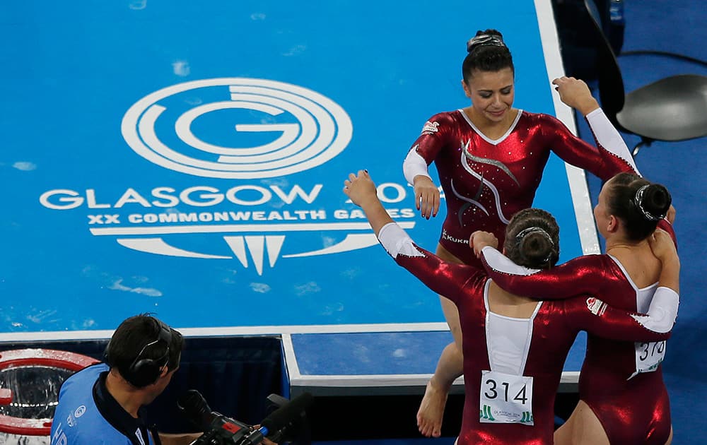 Claudia Fragapane of England walks into the arms of her teammates Ruby Harrold and Hannah Whelan after her floor routine at the women's individual all-round gymnastic competition at the Commonwealth Games Glasgow 2014, in Glasgow, Scotland.