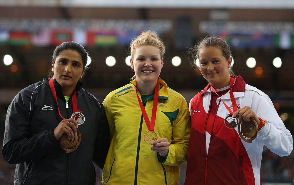 Dani Samuels, centre, of Australia holds up her gold medal as she poses for photographs, with Seema Punia , left of India, silver medal and Jade Lally of England who won the bronze medal following the medal ceremony for the women's Discus final at Hampden Park Stadium during the Commonwealth Games 2