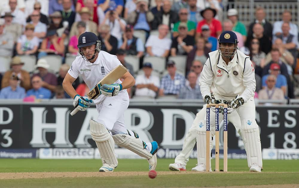 England's Jos Buttler takes a run as India's captain MS Dhoni looks on, on the second day of the fourth test match of their five match series at Old Trafford cricket ground, in Manchester, England.