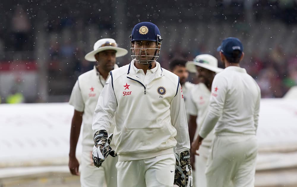 India's captain MS Dhoni walks from the pitch as rain begins to fall on the second day of the fourth test match of his team's five match series against England at Old Trafford cricket ground, in Manchester.