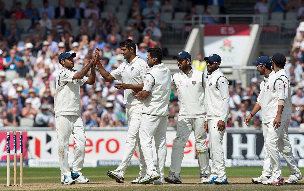 India's Pankaj Singh celebrates with teammates after taking the wicket of England's Joe Root, caught by MS Dhoni for 77, on the third day of the fourth test match of his side's five match series against England at Old Trafford cricket ground, in Manchester, England.