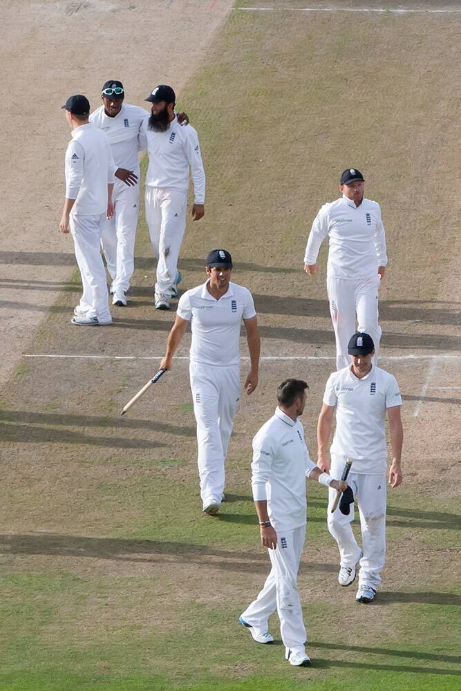 England captain Alastair Cook, center, walks from the pitch with his players after their innings and 54 run win against India on the third day of the fourth test match of their five match series at Old Trafford cricket ground, in Manchester, England.