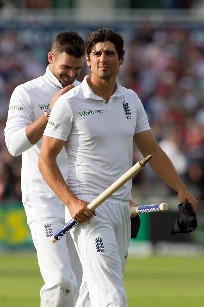 England captain Alastair Cook, centre, and James Anderson walk from the pitch after their team beat India on the third day of the fourth test match of their five match series at Old Trafford cricket ground, in Manchester, England.