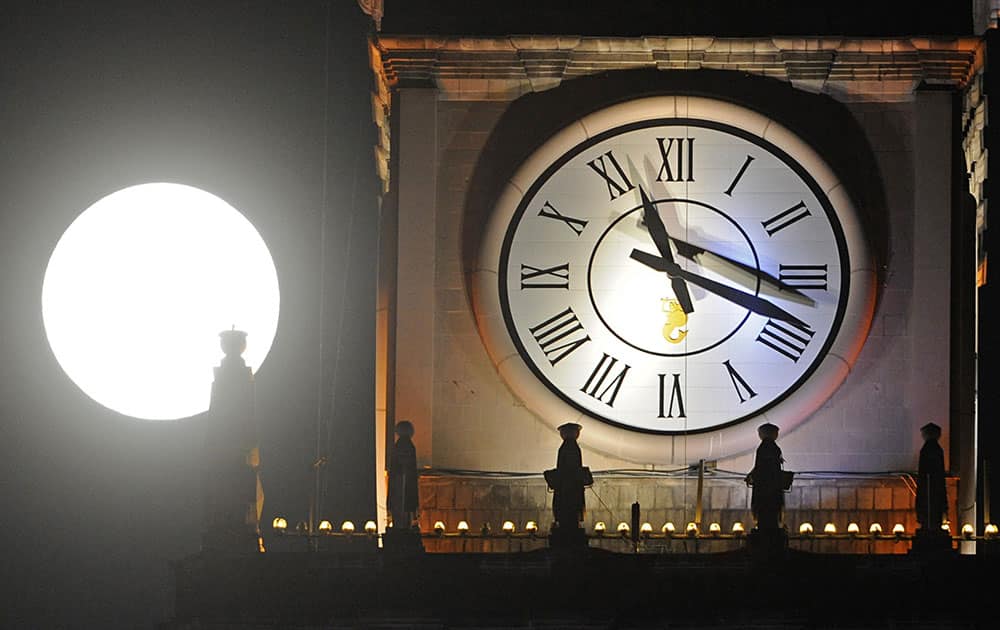 A supermoon rises next to a clock on top of the Palace of Culture in Warsaw, Poland.