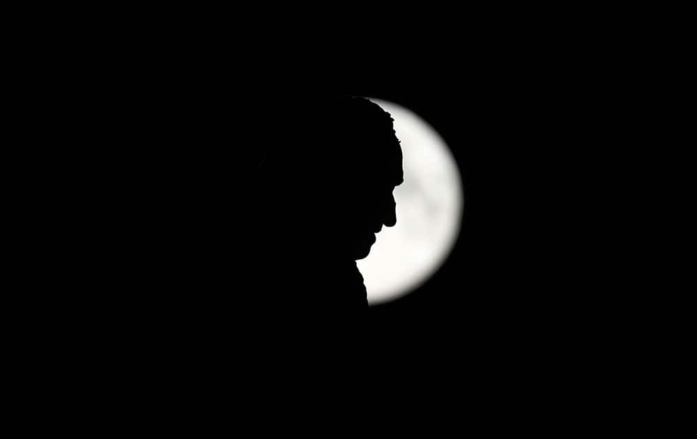 A monument to Christopher Columbus stands against the perigee moon, also known as a supermoon, in Madrid.