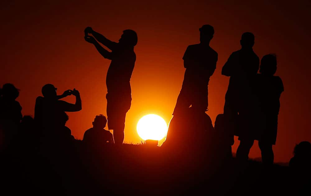 The sun sets as people take photos and gather in the park waiting for a perigee moon, also known as a supermoon, to appear in Madrid.