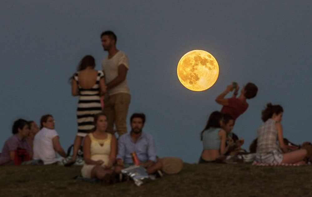 People gather in the park as a perigee moon, also known as a supermoon, rises in Madrid.