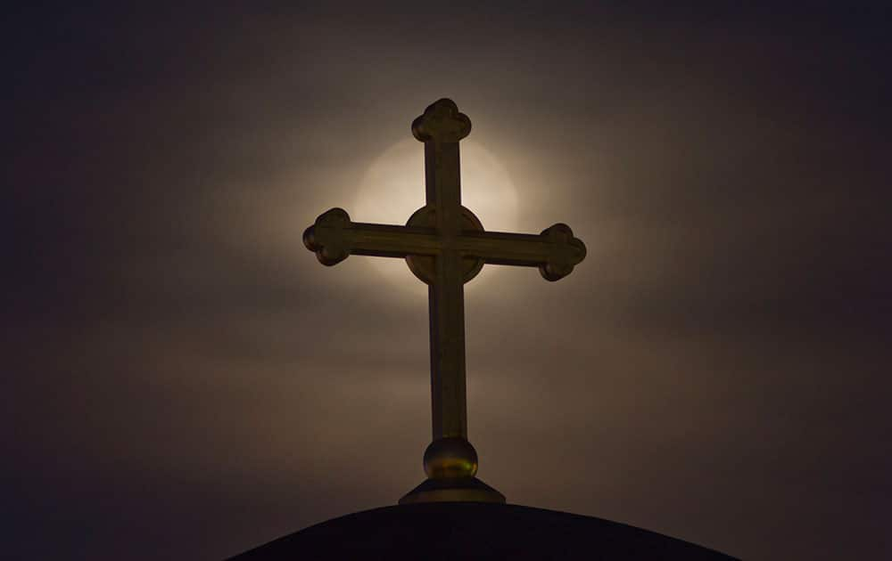 The moon appears behind a cross on the unfinished Serbian Orthodox church Christ the Saviour Cathedral, in Kosovo capital Pristina.