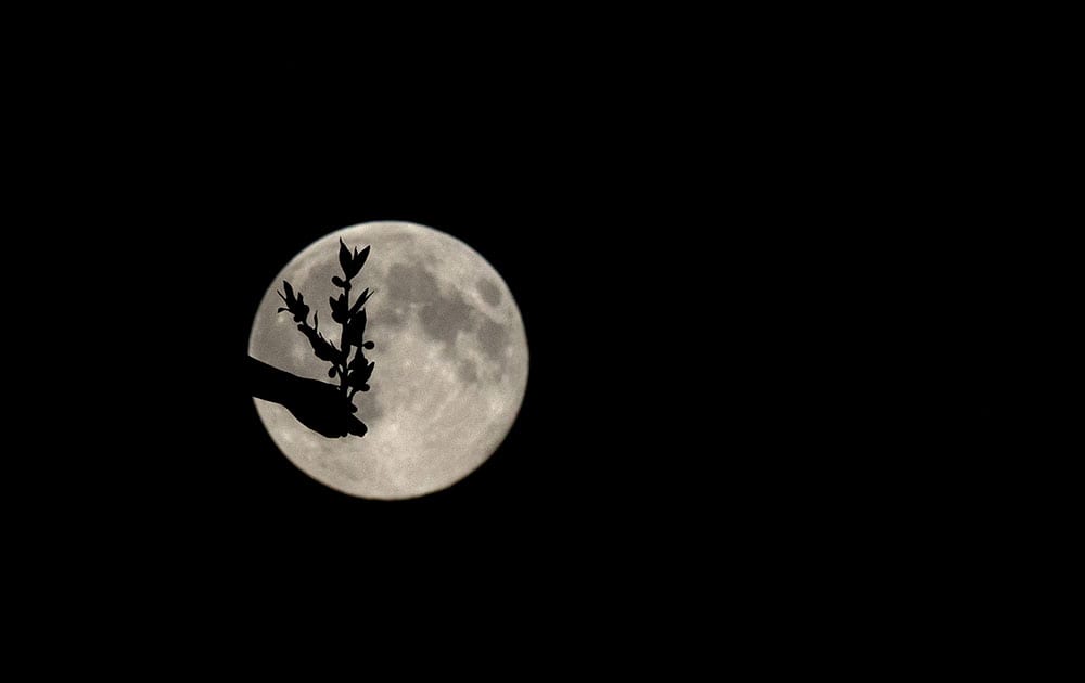 A supermoon appears behind the Angel of Peace sculpture, in London.