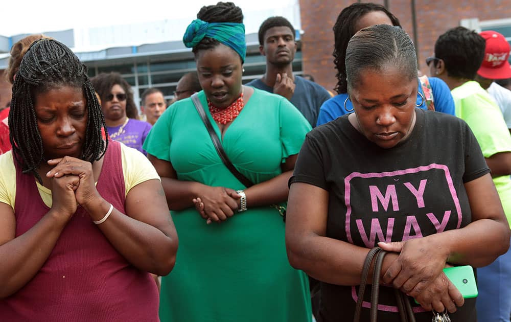 A prayer vigil was held in front of the Ferguson, Mo. police department on Sunday, Aug. 10, 2014, one day after a Ferguson officer shot and killed Michael Brown. From left are Martha Hightower, Leah Clyburn and Marie Wilson. `I`m just tired of (the police) getting away with killing our youths,` said Hightower.