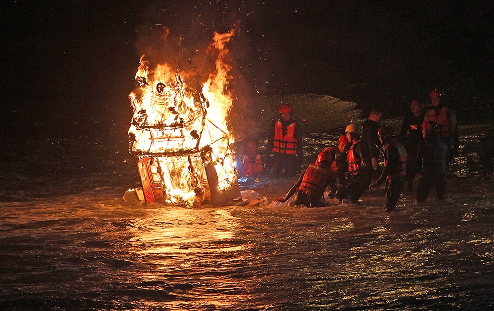 Worshippers guide a burning model house into the ocean as an offering to appease wandering ghosts during the Chinese folklore`s mid-summer`s Ghost Month Festival in Keelung, Taiwan.