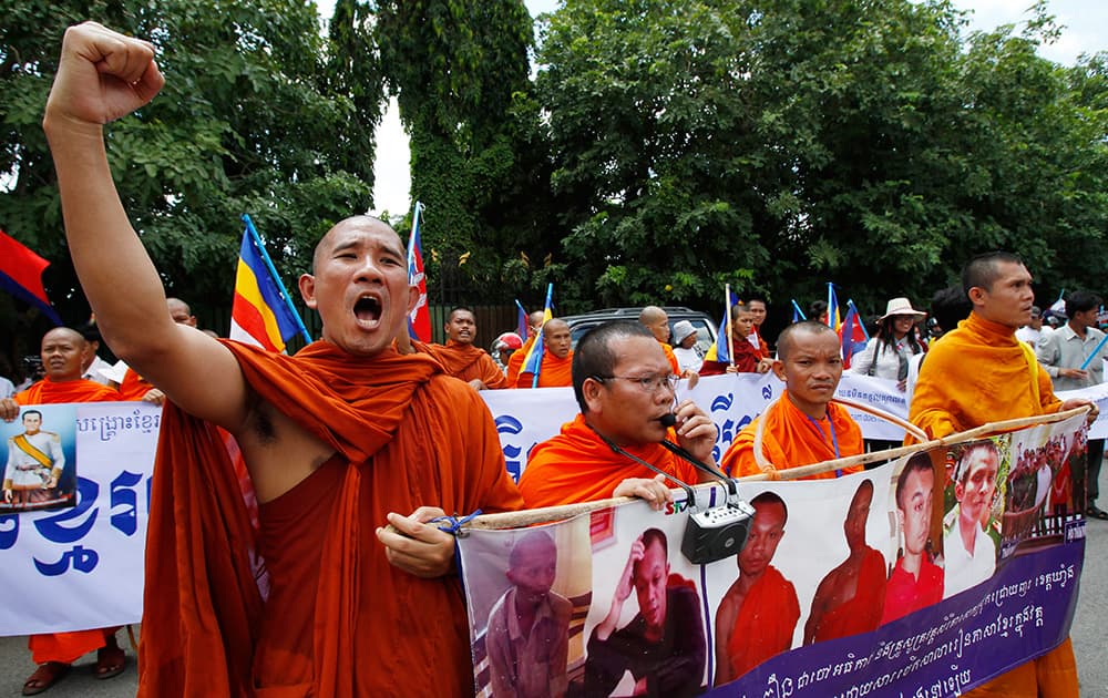 A Cambodian Buddhist monk, left, shouts slogans during a protest in front of Foreign Ministry during the delivering a petition, in Phnom Penh, Cambodia.