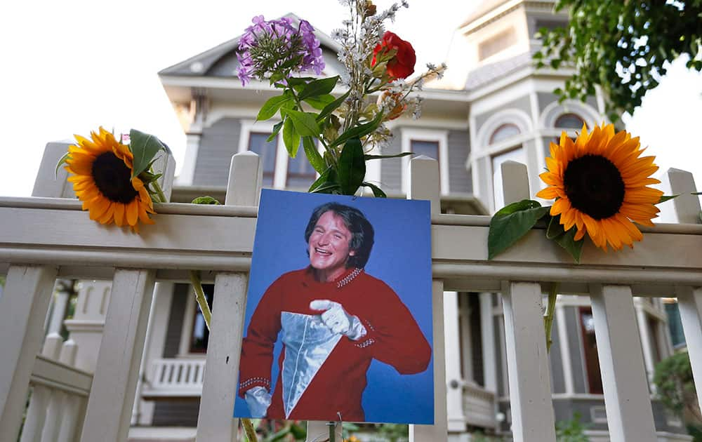 A photo of the late actor Robin Williams as Mork from Ork hangs with flowers left by people paying their respects, in Boulder, Colo.