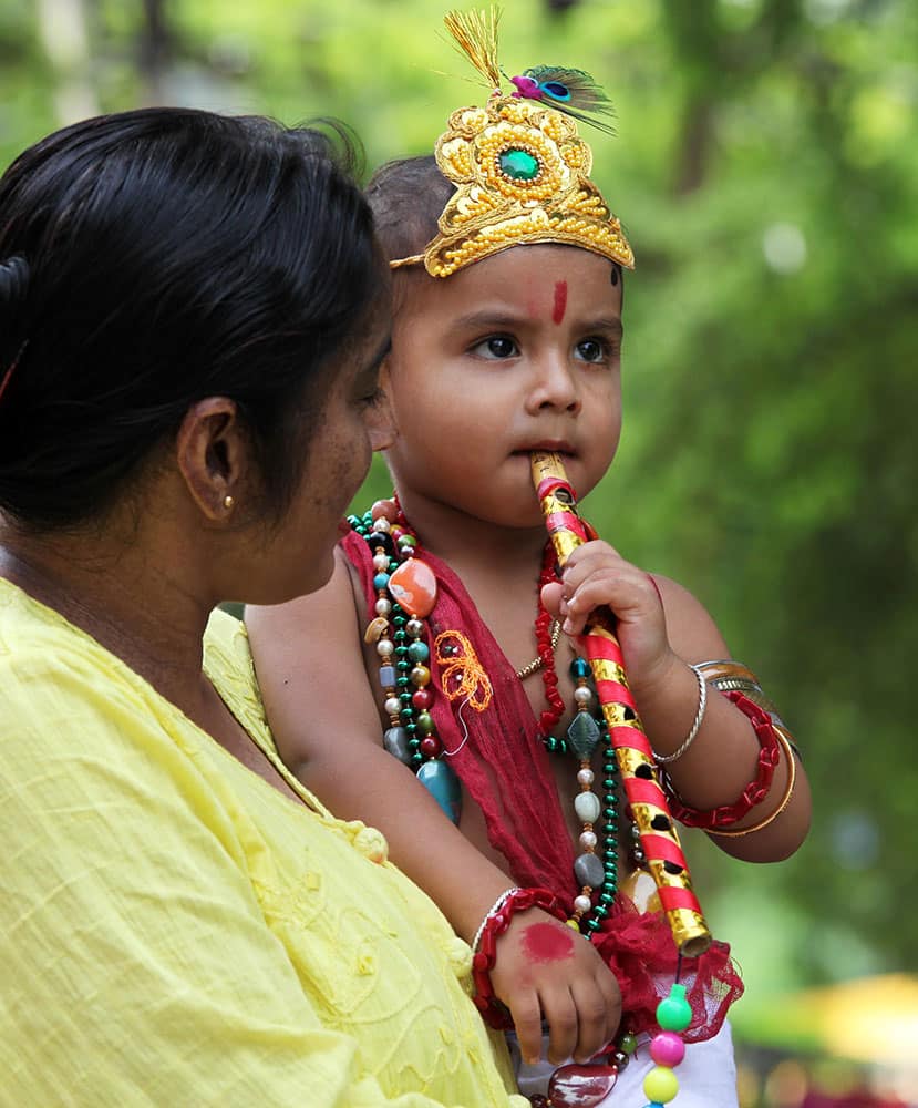 A woman carries a child dressed as Hindu God Krishna in Allahabad.