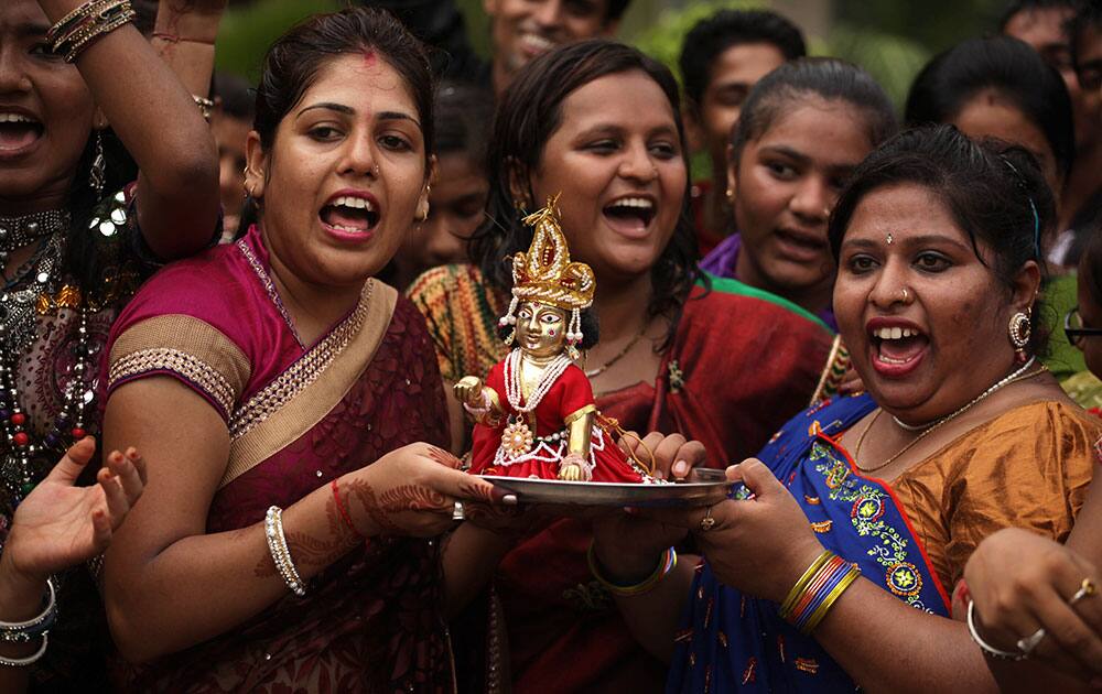 Indian teachers hold an idol of Hindu god Krishna and sings devotional songs during Janmashthami celebrations at a school in Ahmadabad.