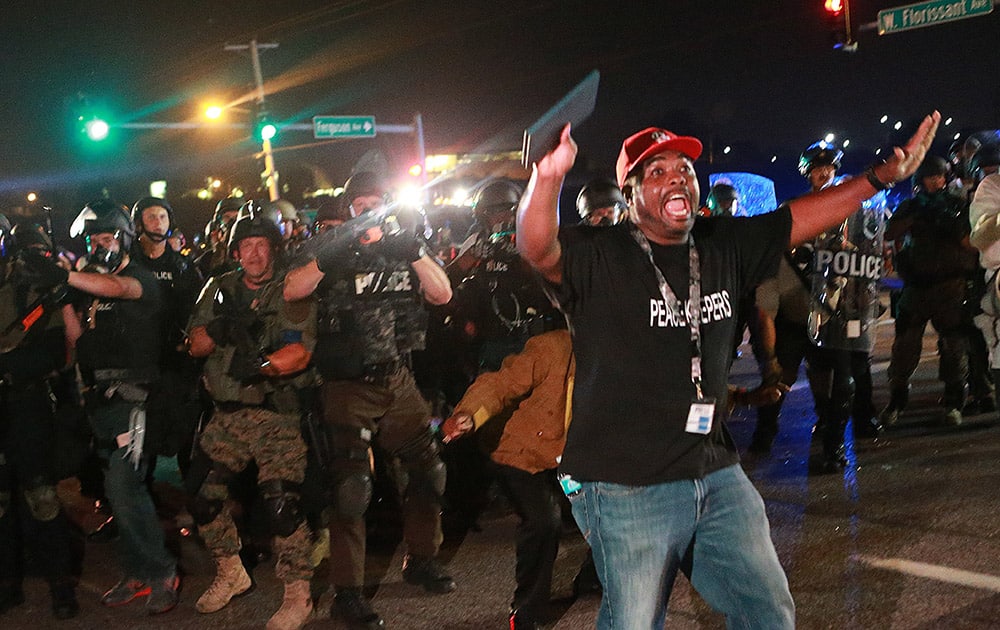 A citizen peacekeeper tries to keep protesters back as police advance, in Ferguson, Mo.