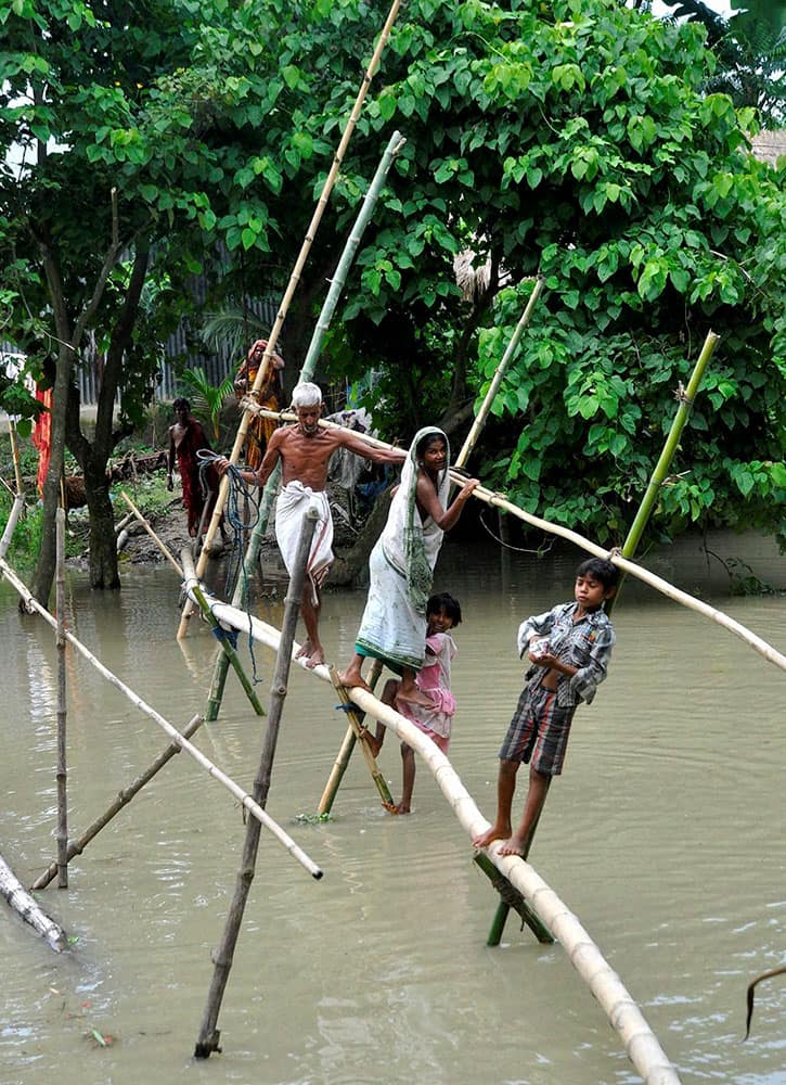 Indian villagers use a bamboo structure to move across a flooded village in Morigaon district of northeastern Assam state, India.