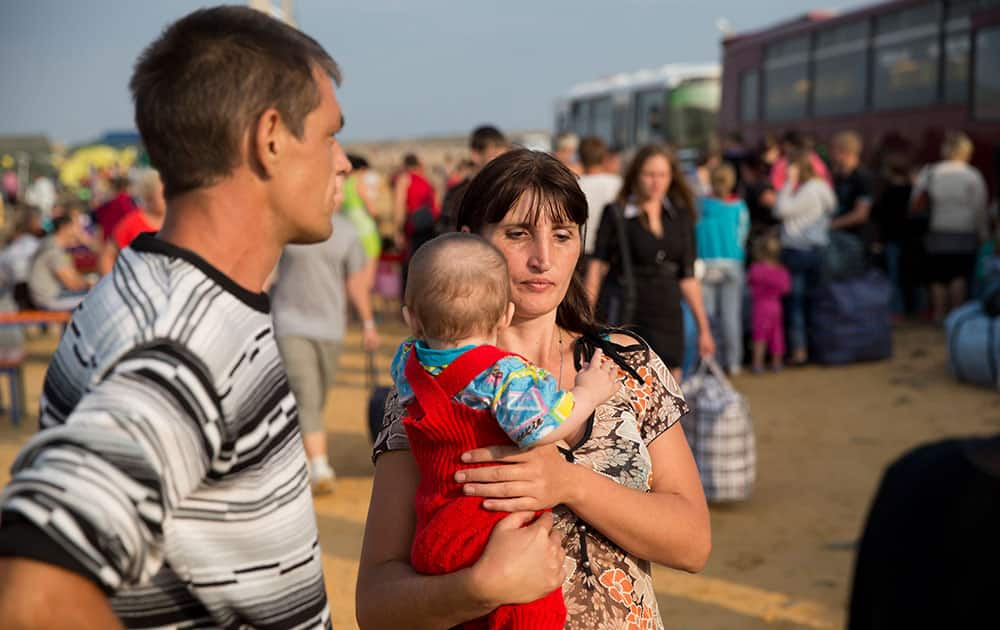 A family displaced by fighting in Ukraine wait to board a bus ahead of their journey by train to the Russian Siberian city of Irkutsk, where they are being relocated, at a refugee camp set up by the Russian Emergencies Ministry about 10 kilometers (6 miles) from the Russia-Ukrainian border, near Donetsk, Rostov-on-Don region, Russia.