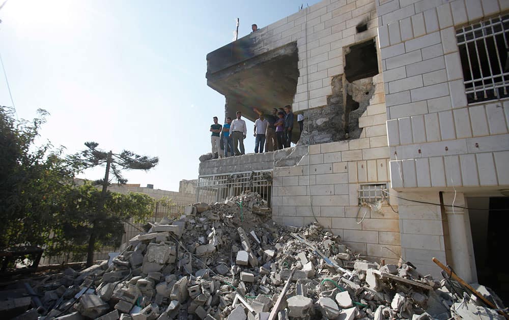 Palestinians stand in what is left of the home of Amer Abu Aisheh, one of three Palestinians identified by Israel as suspects in the killing of three Israeli teenagers, after it was demolished by the Israeli army in the West Bank city of Hebron.