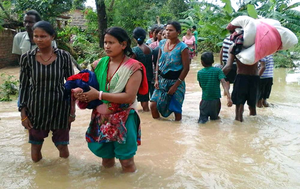 Nepalese villagers carry their belongings while wading through a flooded street to move to safer ground, at Bardia, in western Nepal.