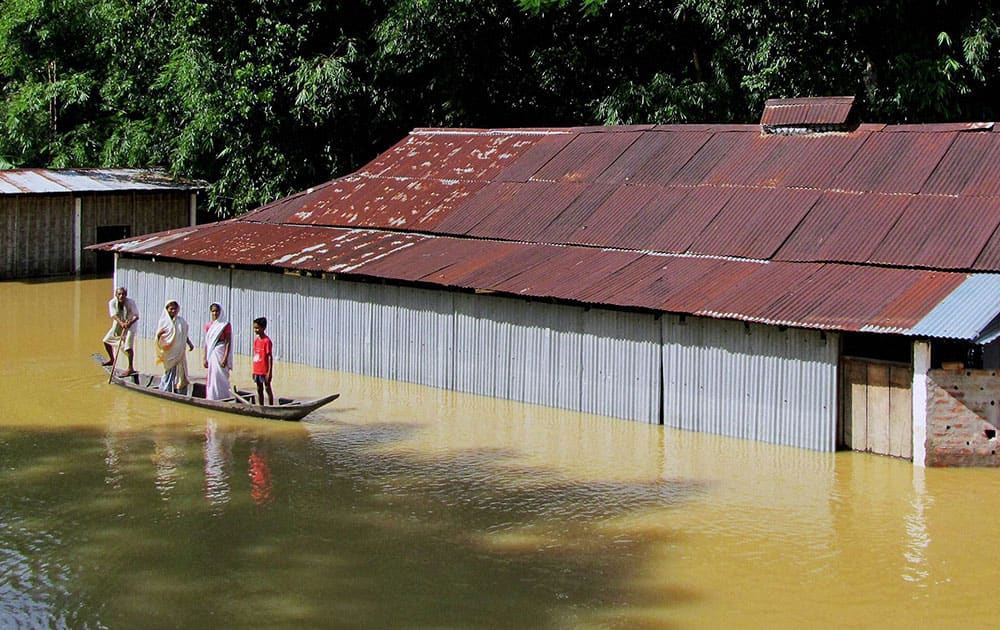 A family shifting to safer place by a boat in flood affected Teok, Jhanjimukho in Jorhat district of Assam. 