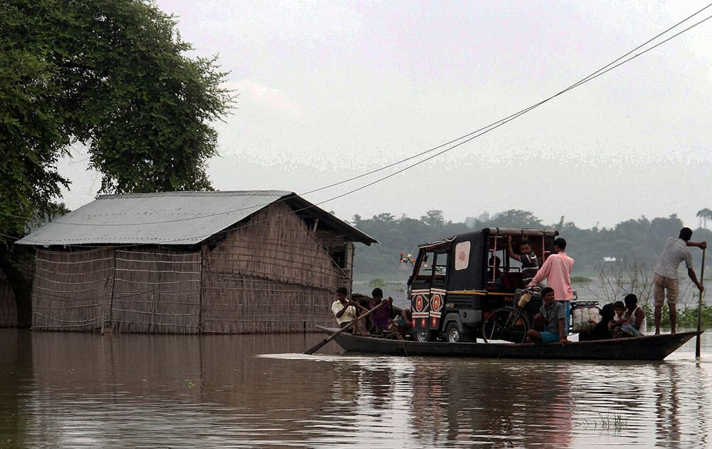 Villagers carry an auto rickshaw on a boat to safer areas in flood affected Balimukh village of Morigaon district, Assam.