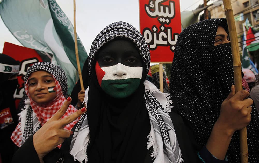 A supporter of Pakistani religious party Jamaat-e-Islami, with her face painted with a representation of the Palestinian flag, and others rally against the Israeli bombings in the Gaza, in Karachi.