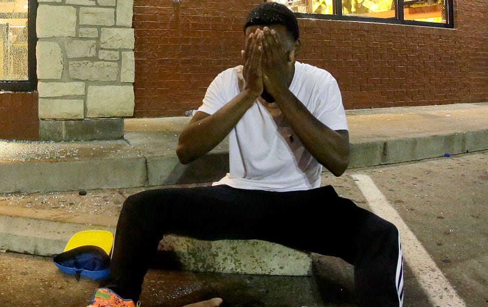 A man tries to recover after being hit by tear gas when police dispersed a crowd, as they staged a protest for Michael Brown, who was killed by a police officer last Saturday in Ferguson, Mo.