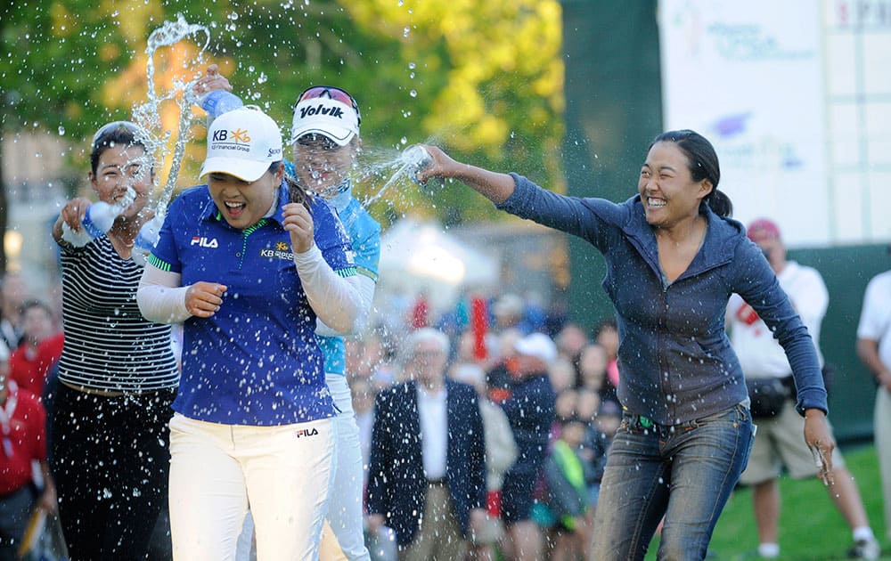 Jenny Shin, left, Meena Lee, center, and Illhee Lee, right, spray Champion Inbee Park after she won the Wegmans LPGA golf championship in Pittsford, N.Y.