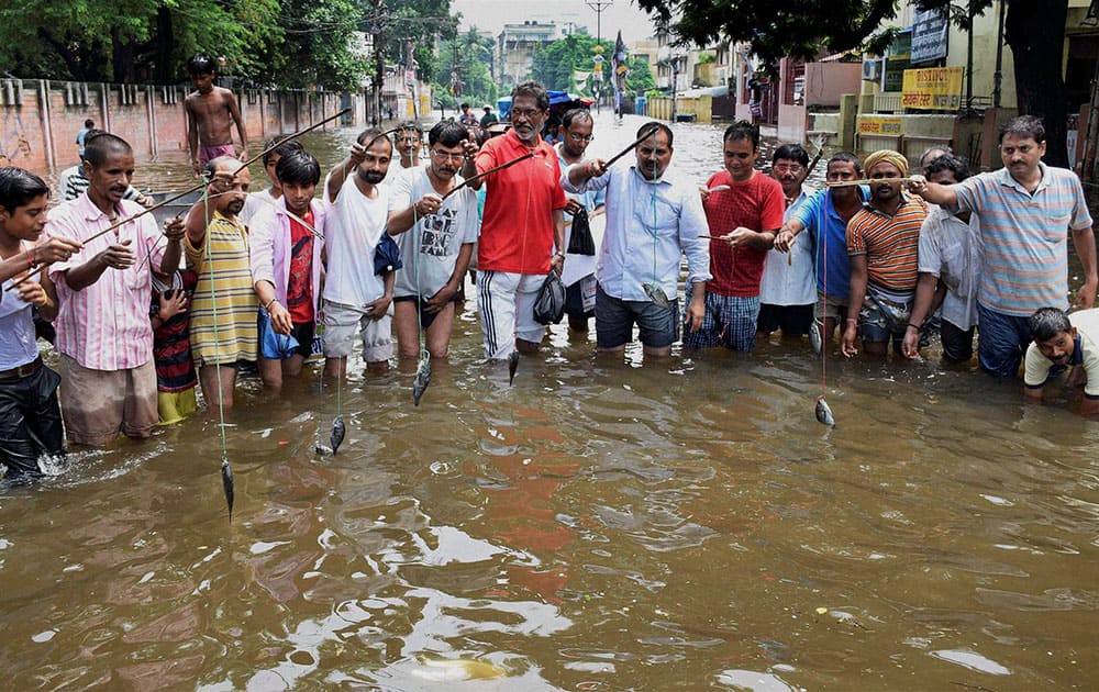 Locals simulate fishing during a protest against the Bihar Government over waterlogging in Patna.