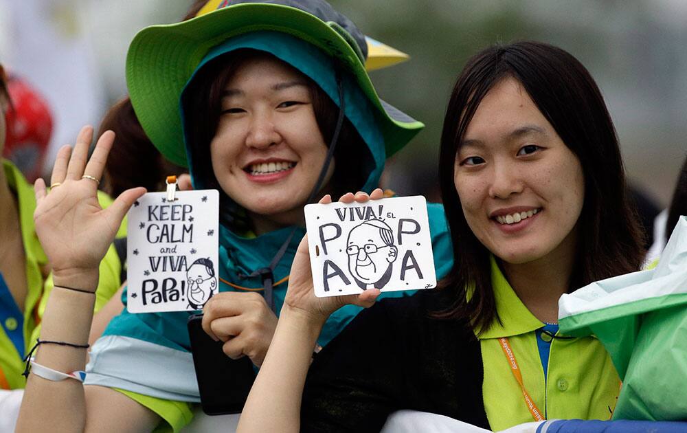 The faithful waves to photographers as they wait for the start of a mass to be conducted by Pope Francis, concluding the 6th Asian Youth Day in Haemi, South Korea.