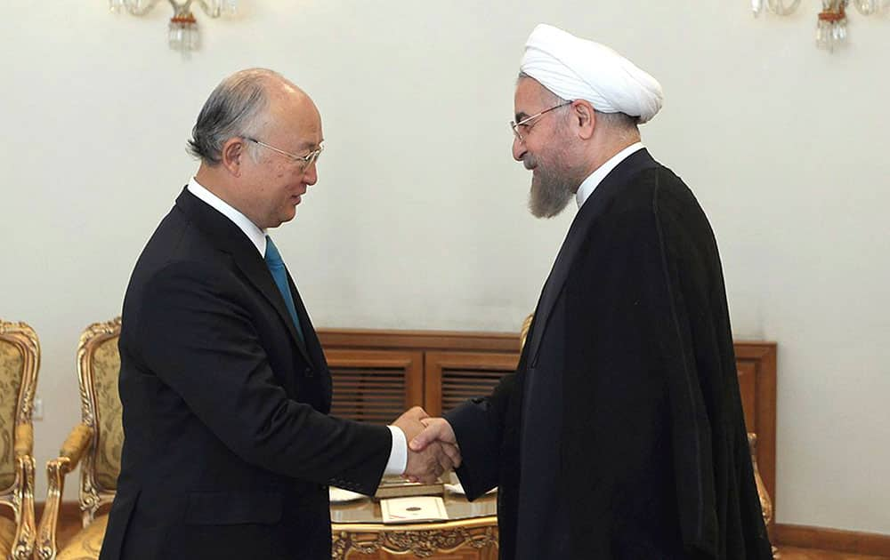 In this photo released by the official website of the office of the Iranian Presidency, Iran`s President Hassan Rouhani, right, shakes hands with Director General of the International Atomic Energy Agency Yukiya Amano at the start of their meeting in Tehran, Iran.