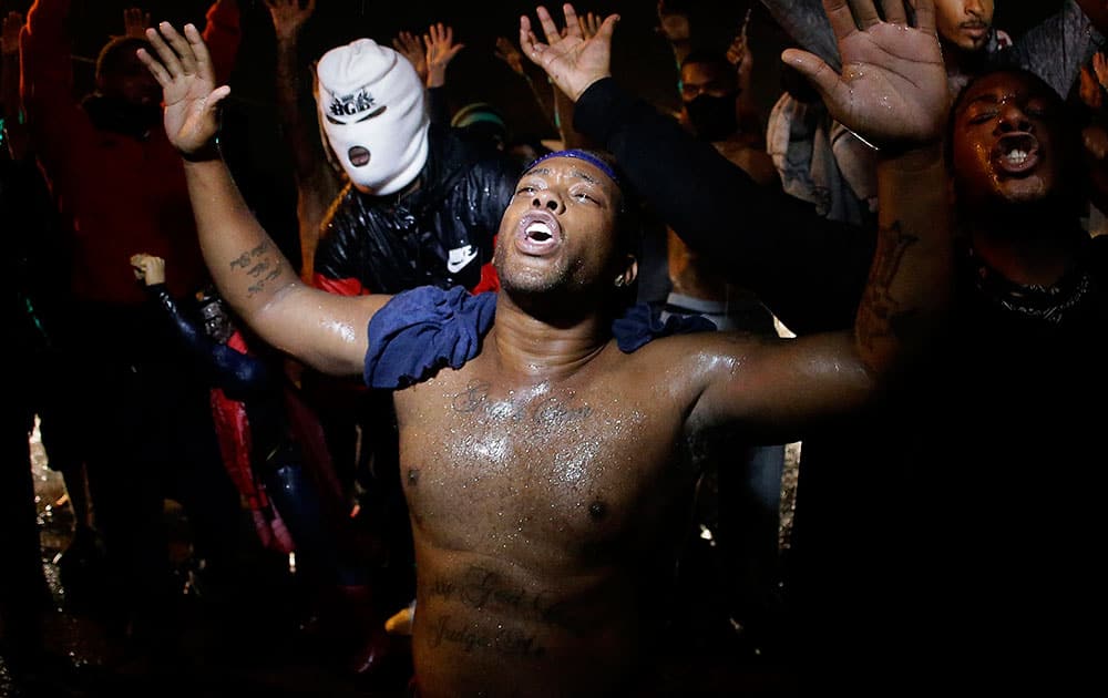 People defy a curfew Sunday, Aug. 17, 2014, before smoke and tear gas was fired to disperse a crowd protesting the shooting of teenager Michael Brown last Saturday in Ferguson, Mo.