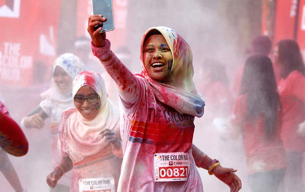 A participant takes a selfie as she runs through a `color station` during the five-kilometer color run event in Kuala Lumpur, Malaysia.