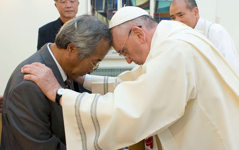 In this photo provided by the L` Osservatore Romano, Pope Francis baptizes Lee Ho Jin, the father of one of the children who died in South Korea`s April ferry disaster, in Seoul, South Korea.