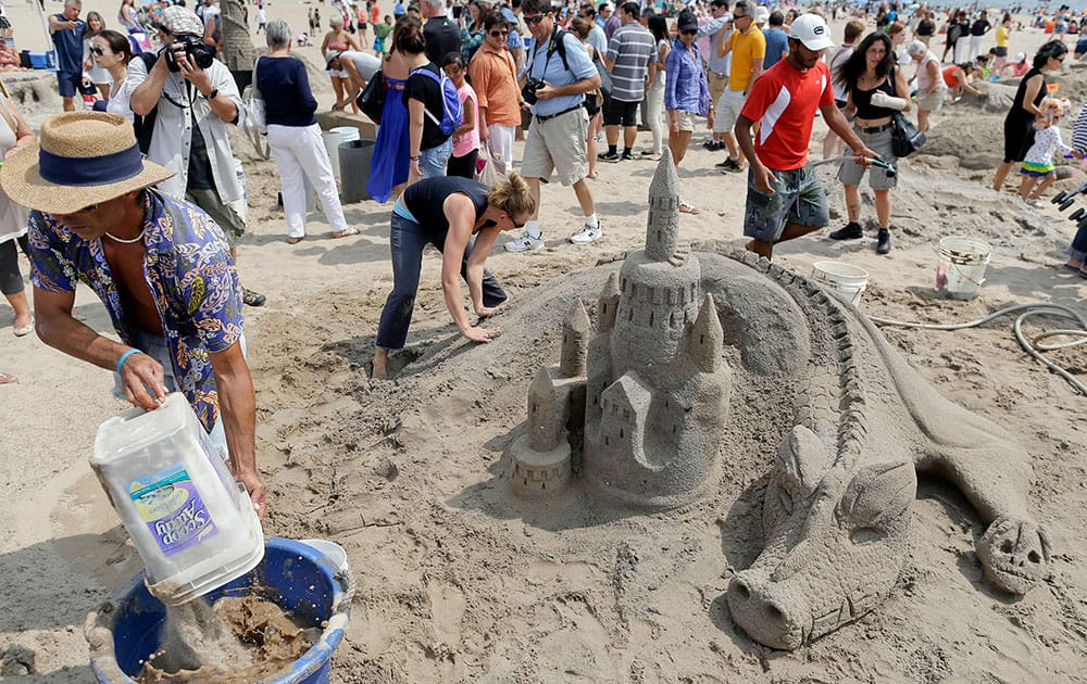 William Petrosino, left, mixes sand with water while carving a dragon and castle with Dartya Feklistova during a sand sculpting contest in the Coney Island neighborhood of the Brooklyn borough of New York.